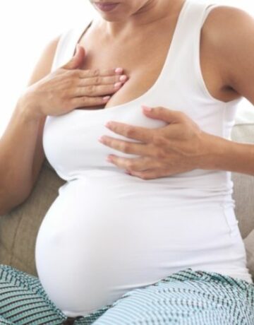 Frau massiert Brust gegen Brustspannen in der Schwangerschaft
