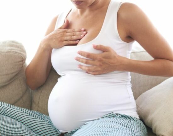 Frau massiert Brust gegen Brustspannen in der Schwangerschaft