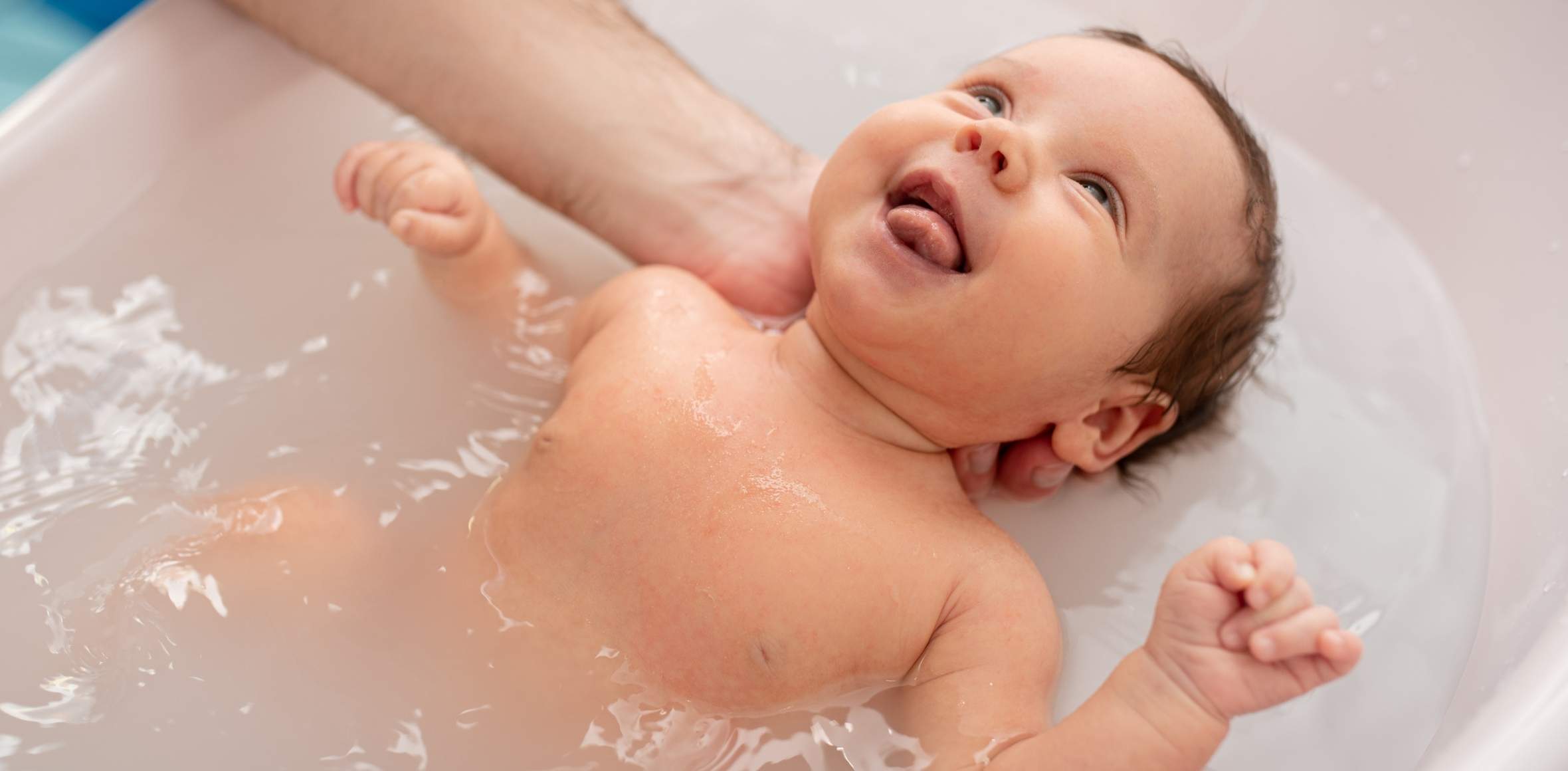 Baby liegt lachend in einer Badewanne