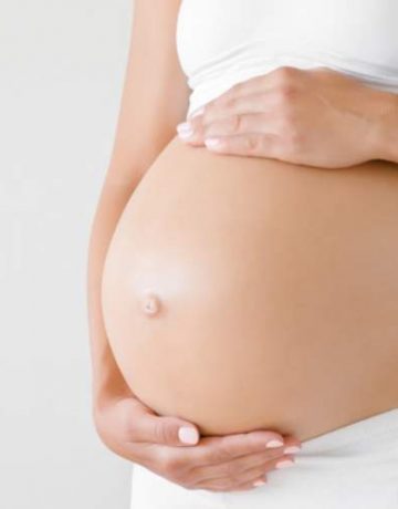 schwangere frau streichelt sich ueber ihren babybauch