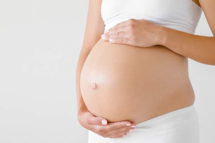schwangere frau streichelt sich ueber ihren babybauch